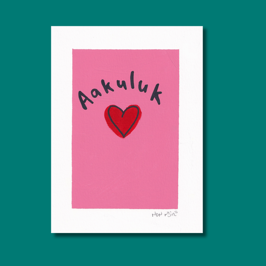 Hand-painted artwork titled ‘Aakuluk,’ featuring the Inuktitut word for ‘I love you’ above a red heart on a bright pink background. The piece rests against a teal backdrop, evoking tenderness, warmth, and Northern simplicity through vivid color contrast and gentle brushwork.