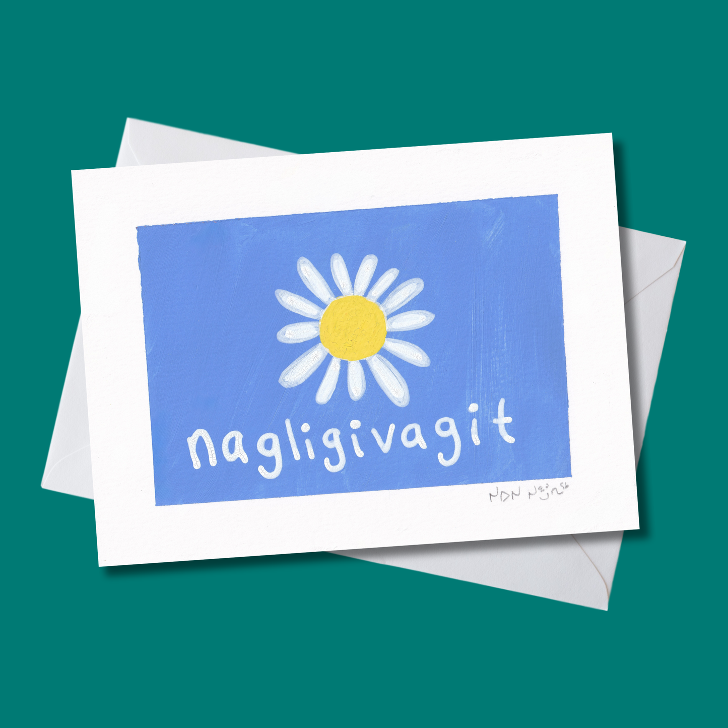 Angled view of a hand-painted artwork titled ‘Nagligivagit,’ featuring a single white daisy with a bright yellow center on a vivid blue background. The Inuktitut word ‘Nagligivagit,’ meaning ‘I love you,’ appears in soft white text beneath the flower. The piece rests on a deep teal backdrop with white envelope, emphasizing the artwork’s bright, joyful palette and tender sentiment.